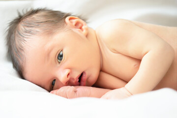 The face of a newborn baby with open eyes and small arms.