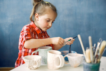 Child in a pottery. Master make a dishes. Kid works with a clay. Ceramics theme.