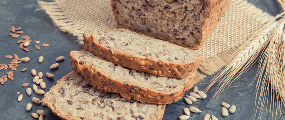 Wholegrain bread for breakfast, ingredients for baking and ears of rye or wheat grain