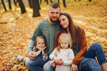 Fototapeta premium Family in a autumn park. Woman in a red sweater. Cute childrens with parents