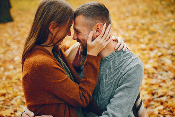 Fototapeta premium Couple in a park. Woman in a brown sweater. Man with a beard