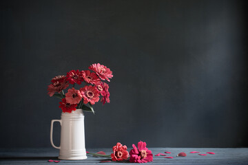pink flowers in white jug on dark blue background