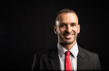 Handsome and smiling man in suit. Close up. Black background.