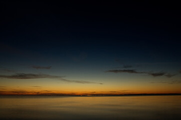Fototapeta na wymiar Krajobraz zachód słońca nad wodą z pięknie oświetlonym niebem