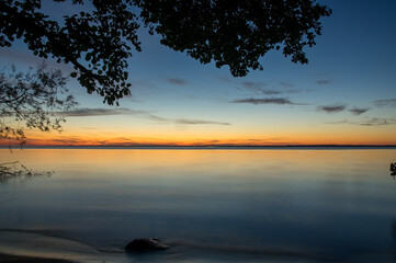 Krajobraz zachód słońca nad wodą z pięknie oświetlonym niebem © Monika