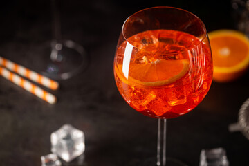 Aperol spritz cocktail in glass with fresh orange on dark background