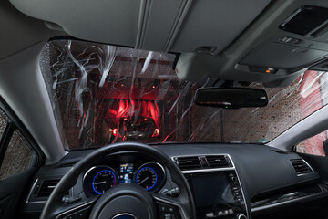Automatic car wash with conveyor belt. A view through the windshield from the car that is pulled to...