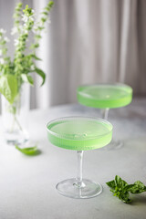 Summer green cocktail with lime, basil and ice in a crystal glass