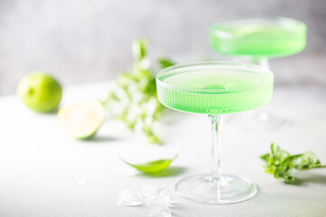 Summer green cocktail with lime, basil and ice in a crystal glass
