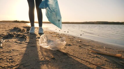 Teamwork cleaning plastic on the beach. Volunteers collect trash in a trash bag. Plastic pollution and environmental problem concept. Voluntary cleaning of nature from plastic. Greening the planet - Powered by Adobe