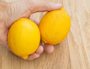 Two fresh lemons in a man's hand. The benefits of lemon
