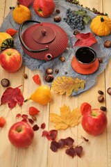 autumn tea party.Thanksgiving Day. Red teapot, a cup of tea, apples,pumpkin, chestnuts and autumn leaves on a light wooden table.Autumn cozy mood.Fall season