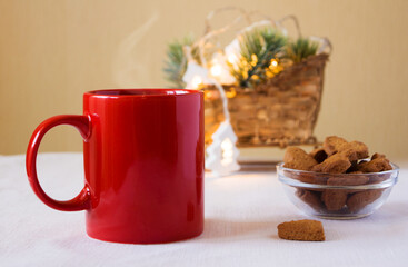 Obraz na płótnie Canvas Red mug with coffee and cookies on the table. Next to the Christmas decoration and garland. New year mood