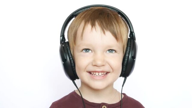 A portrait of a smiling little boy with funny teeth wearing big headphones close up