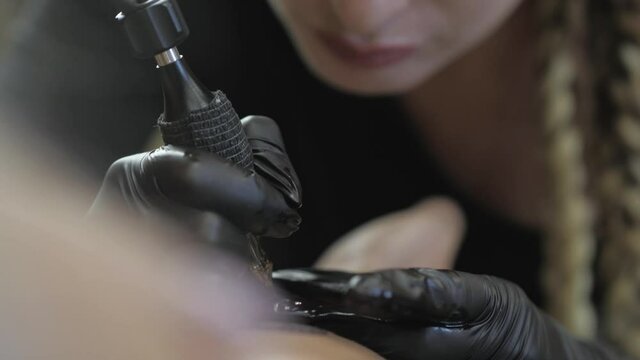 close-up of the process of getting a tattoo by a tattoo artist. a girl tattoo artist makes a tattoo. tattoo master. 4k