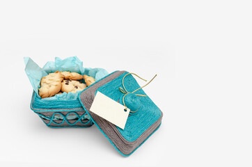 Cesta tejida con hilo de yute azul y gris con galletas horneadas en casa. Tarjeta en la tapa para...