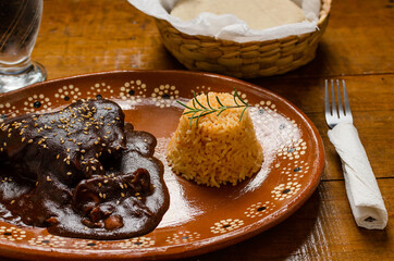 Mole, comida tipica mexicana. Servida en plato de barro sobre mesa de madera.