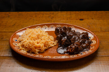 Mole, comida tipica mexicana. Servida en plato de barro sobre mesa de madera.