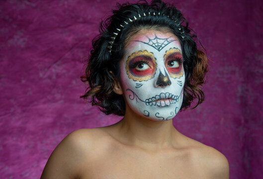 Mujer joven millennial bonita maquillaje catrina mexicana latina día de los muertos halloween calavera cara pintada festividad disfraces fondo rosa colorido punk moderna urbana modelo