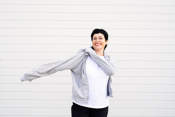 Senior woman waring gray jacket standing outdoors on gray solid background