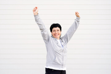 Senior woman stretching her arms outdoors on the sports ground