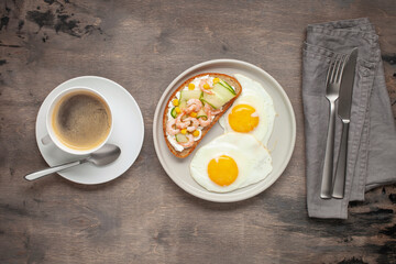 Sandwich with cheese, cucumber and shrimp, fried eggs on a plate and coffee on the table. Healthy breakfast. Top View
