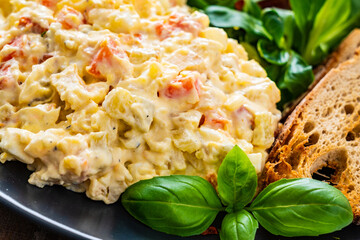 Vegetable mayonnaise salad with toasts on wooden table
