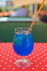 Blue curacao cocktail drink in glass with ice and lemon outside. Cold refreshing summer beverage.