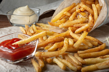 French fries with salt and cream cheese with sauce on the table. French fries sprinkled with salt. French fries with ketchup.