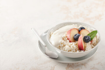 Healthy breakfast or dessert - cottage cheese with peaches and berries in a bowl on the table