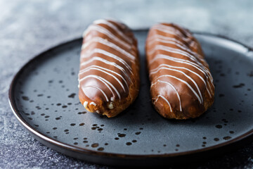 Fresh eclairs on a plate with chocolate glaze