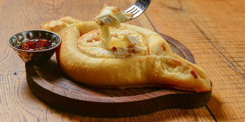 Khachapuri with brie cheese served on a wooden board. Traditional meal, Georgian cuisine concept