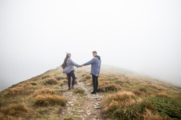 Fototapeta na wymiar young couple traveling in the mountains, the road is in fog