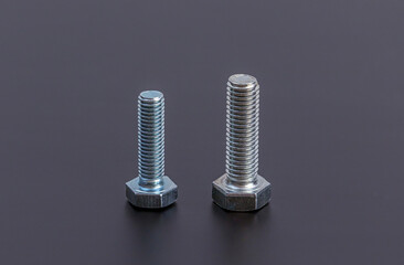 Fixing material. Construction supplies. Metal bolts and nuts on a dark background