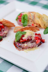 Traditional Italian appetizer Bruschetta with roasted tomatoes, mozzarella cheese, strawberry, garlic and herbs.