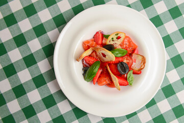 Summer salmon salad with strawberry, tomato, olives and basil in a white plate. Traditional Italian cuisine concept.