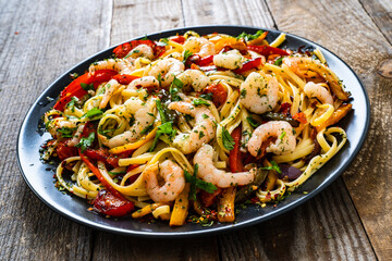 Spaghetti with prawns and vegetables on wooden background
