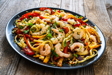 Spaghetti with prawns and vegetables on wooden background
