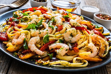 Spaghetti with prawns and vegetables on wooden background
