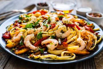 Spaghetti with prawns and vegetables on wooden background

