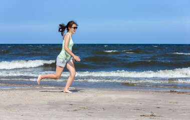 Fototapeta na wymiar Teenage girl running, jumping on beach 
