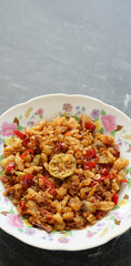 Salted shredded fish or abon is a traditional Indonesian food made from mashed salted fish, it tastes salty, spicy and delicious. Served on a white plate and stone pad.