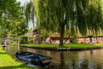 Obraz premium Weeping willow and boat in front of a traditional Dutch house in Giethoorn