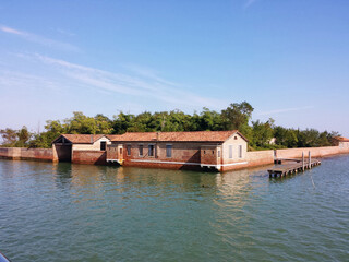 Flooded building and brick fence. Behind the fence is dense vegetation.