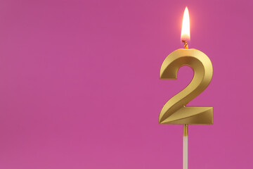 Burning golden birthday candle on pink background with copy space, number 2