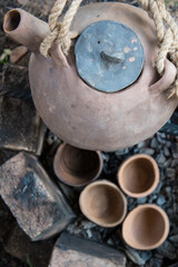 A steaming teapot and tea cups. Tea preparation in a clay pot on a fire. A camping trip, a journey.