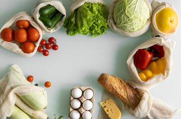 Vegetables, fruits, eggs in reusable eco cotton bags on table. Zero waste shopping concept. Plastic free items. Multi-use, reuse, recycle. Eco friendly canvas grocery bag with tomatoes, pepper, bread.