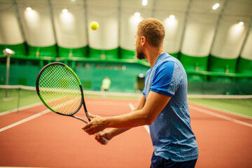 Instructor or coach teaching how to play tennis on a court indoor