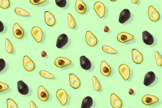 Avocado. Background made from isolated Avocado pieces on green background. Flat lay of fresh ripe avocados and avacado pieces.