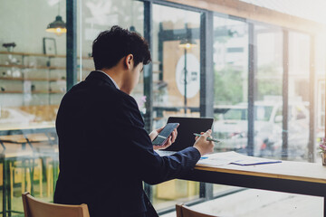 Young asian businessman using mobile phone and text messaging in the office.
